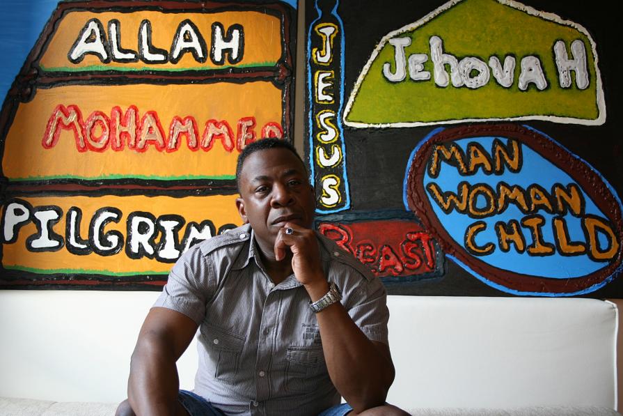 The artist Darrell Black sitting in front of his two expressions of faith